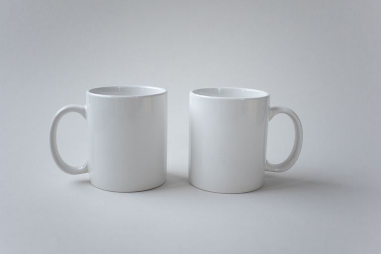 Two white ceramic mugs displayed against a simple white background, showcasing minimalist design.