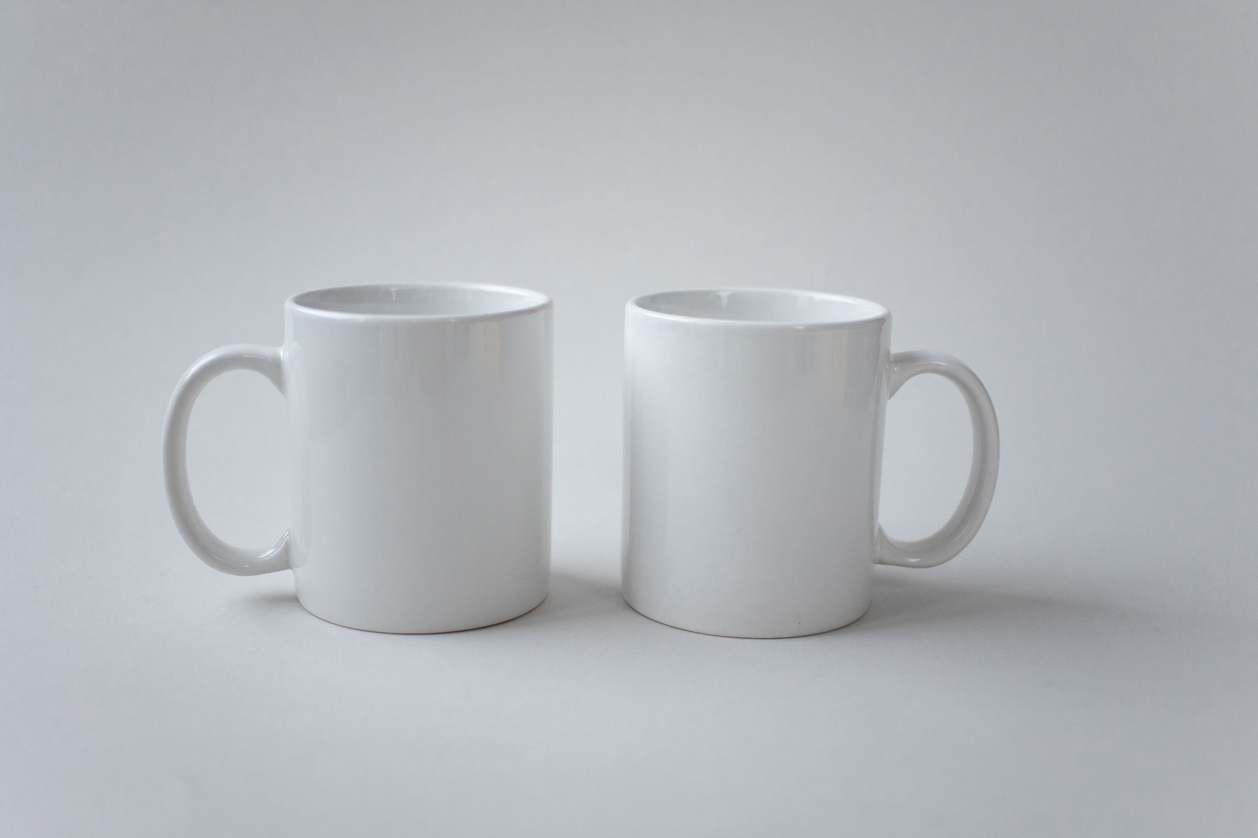Two white ceramic mugs displayed against a simple white background, showcasing minimalist design.